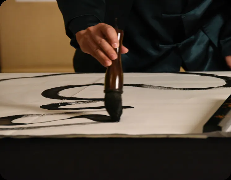 Master calligrapher tracing a Tao Calligraphy stroke with a brush